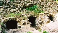 Freigelegte Eingänge an der Nordseite der Ruine, der mittlere Gang führt zum zentralen Kellergewölbe, an den Seiten zwei kleine Kammern (Aufnahme 2002)